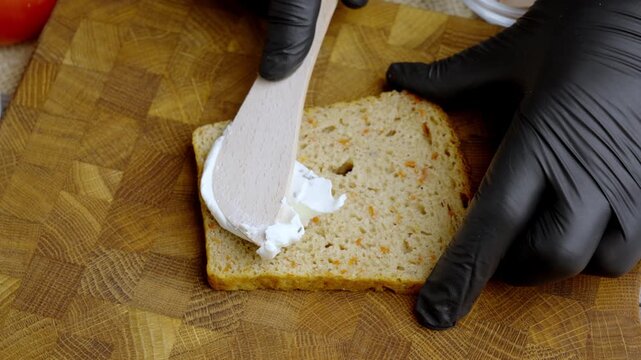Bread prep sequence. Precise application of cream cheese on bread with garlic cloves at edge in calm setting