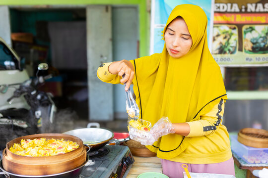 Muslim woman serving Indonesian street food at local stall