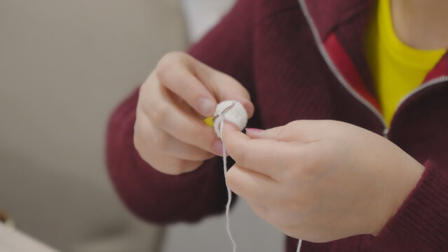 Hands working with needle while performing manual sewing close up in professiona