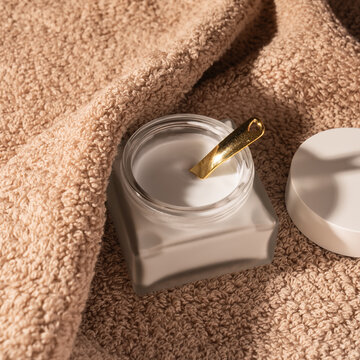 Minimal skin care cream jar with spatula on towel