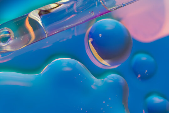 Cosmetic serum drop in neon lighting with glossy bubbles
