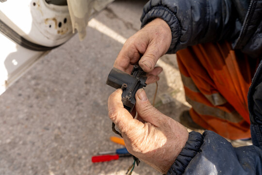 Replacing the central locking motor in a front door. A close-up of a technician's hands holding the central locking motor.