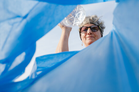 Volunteer collecting plastic bottle during community cleanup