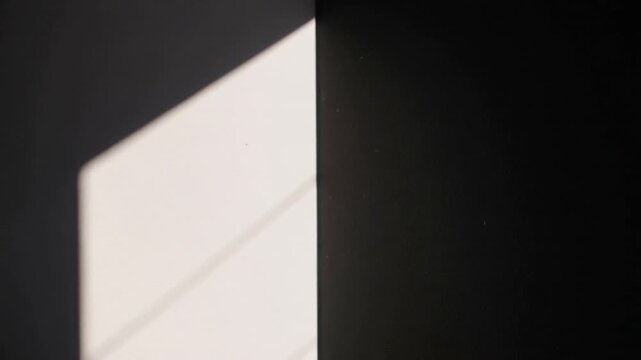 Entering sunlight creating rectangular patch on wall, casting diagonal shadow over seam and dust