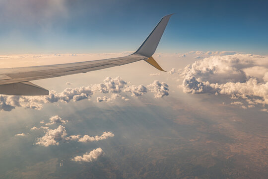 Airplane wing above clouds with sunset sky during flight
