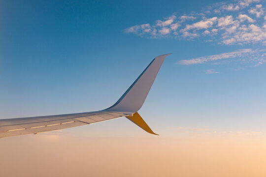Airplane wing above clouds in clear blue morning sky