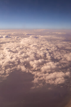 Aerial view of sunlit cloudscape above horizon at dawn