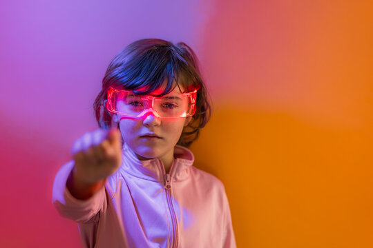 Kid wearing neon smart glasses pointing in futuristic light