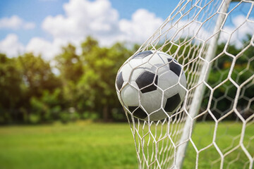 Naklejka premium Soccer ball in soccer goal net . Close-up textured soccer net on soccer goal.