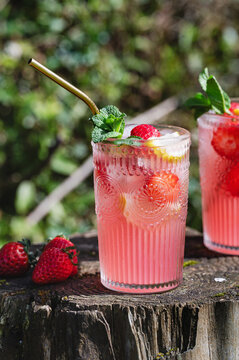 Strawberry lemonade in glass with mint on rustic stump
