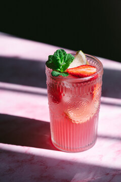 Refreshing strawberry lemonade in glass with mint and lime