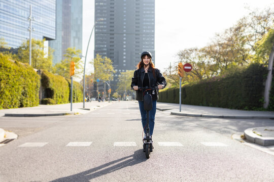 Woman riding electric scooter on sunny city street