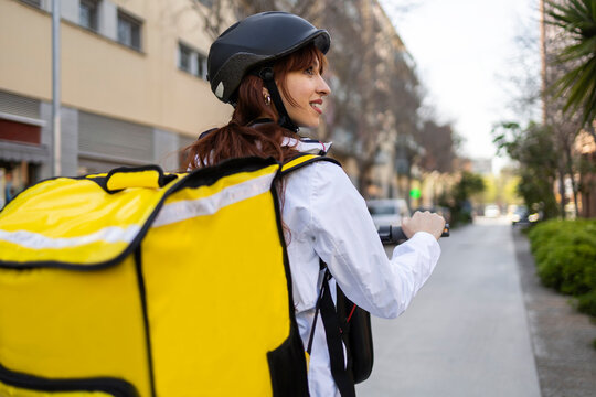 Female food delivery rider with scooter and thermal bag