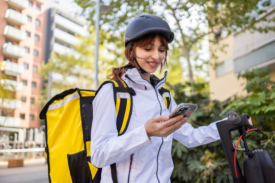 Female food delivery rider checking smartphone in city