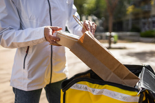 Food delivery driver packing takeaway into insulated bag