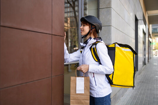 Female food delivery rider at doorway with takeaway bag