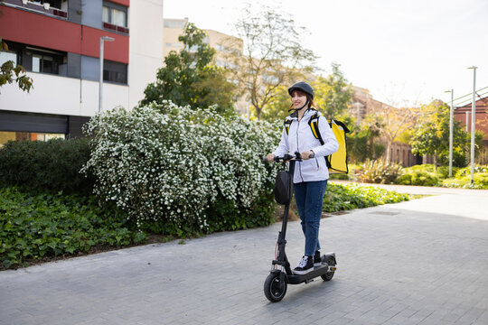 Woman delivery rider on electric scooter in city street