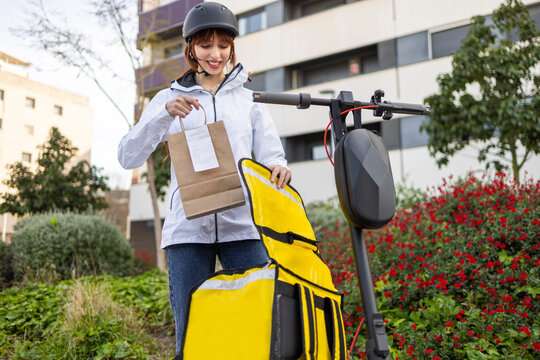 Female delivery rider packing takeaway order for customer
