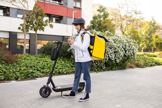 Female food delivery rider with scooter checking phone