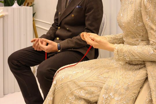Engagement ceremony ritual with couple holding red thread