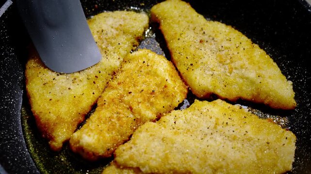 Frying breaded fish. Frying breaded fish. Frying flounder. Vigorous culinary specialist uses spatula to prepare chicken slices efficiently. Dynamic chef skillfully employs spatula techniques
