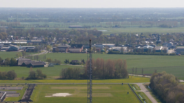 Aerial view of the NAM Grijpskerk UGS facility featuring a tall flare stack surrounded by green fields and the village landscape in Grijpskerk, Groningen, Netherlands.
