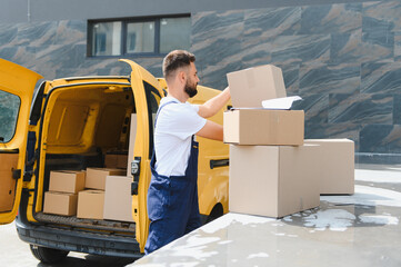 Delivery man unloading cardboard boxes from a yellow van © Serhii