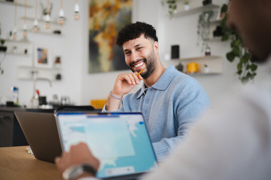 Two colleagues collaborate on a project, one man smiles while holding a pencil, the other focuses on a tablet screen.