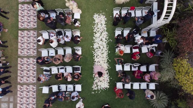 Aerial garden wedding ceremony huachipa lima, rows of white chairs lining petal strewn aisle, bride