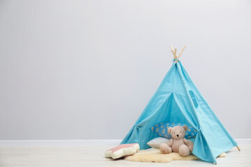 Wigwam, toy bear and pillows in child's room, space for text © New Africa
