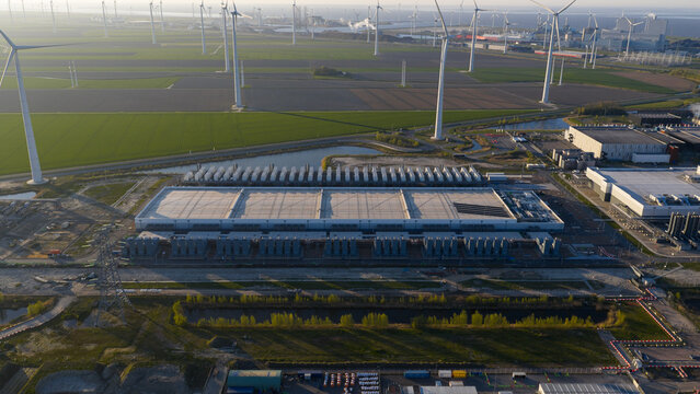 Aerial view of the Google GRQ data center facility surrounded by wind turbines and green fields in Eemshaven, Groningen, Netherlands.