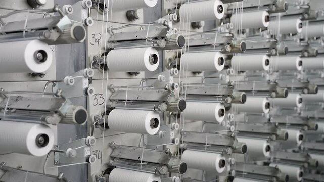 White thread spools rotating on textile machine