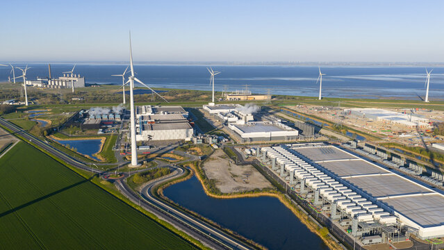 Aerial view of the Google Data Center and wind turbines surrounded by green fields and coastal waters in Eemshaven, Groningen, Netherlands.