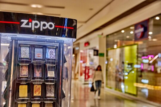 Ambato, Ecuador - June 09, 2025: Zippo display stand showcasing various lighter designs in Mall de los Andes, with shoppers browsing in the background, highlighting retail atmosphere