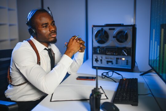 African american police officer records a telephone conversation on a tape recorder. secret agent