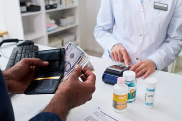 Fototapeta na wymiar Close up of man paying for prescription medicine at pharmacy counter while pharmacist processing card terminal, illustrating healthcare purchase and retail pharmacy marketing