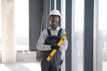 Construction worker holding spirit level smiling at construction site © Serhii