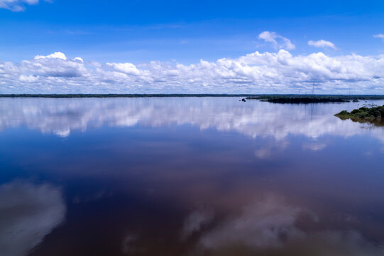 Beautiful landscape view from Tocantins river in the Amazon on summer sunny day. Nature, environment, climate, ecology, ecosystem concept. Clouds reflection on blue calm water.
