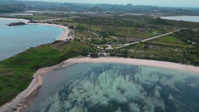 Aerial Green Island Cape With Curved Beaches, Rolling Hills And Farmland Pockets, Long Reef Line Shaping Waves, Secluded Bays, Turquoise Shallow Water Meeting Deep Ocean, Katil beach,Lombok,Indonesia