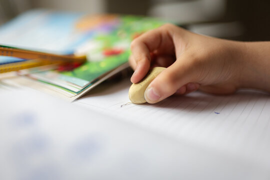 Child hand erasing mistake on notebook homework