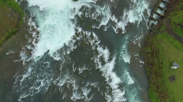 Aerial flight over the beautiful &AElig;giss&iacute;&eth;ufoss waterfall on a summer day located near Hella in south Iceland. Top down view.
