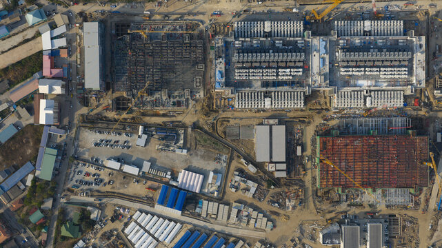 Aerial view of the Bridge Data Center under construction with cranes, industrial structures, and a parking lot in Khlong Tamru, Chon Buri, Thailand.