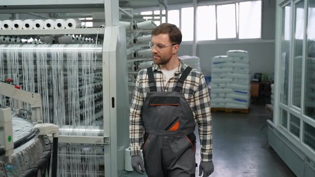 Factory worker checking polypropylene fiber production machine