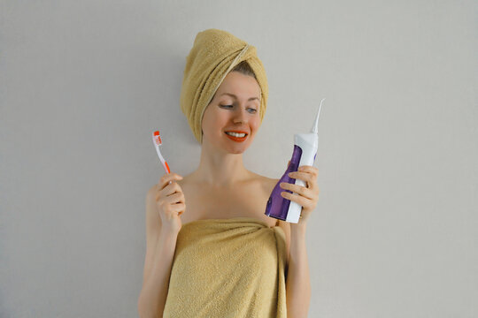 Happy young woman holding toothbrush and oral irrigator