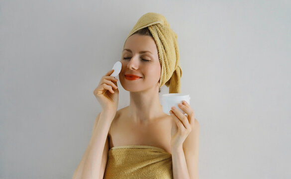 Beauty portrait of happy young woman touches her clean skin applying face cream