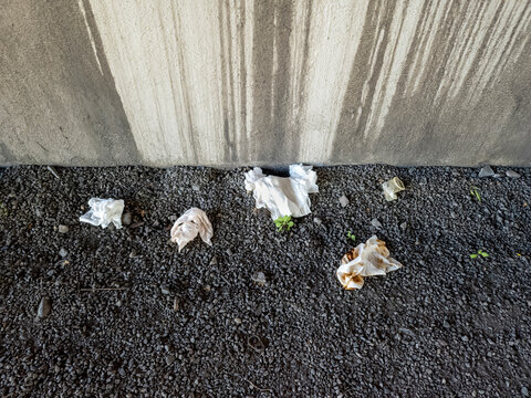 Used condom and wipes discarded beside a concrete wall
