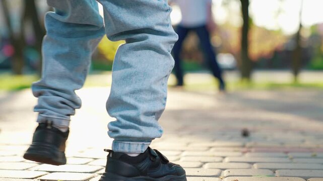 Child foot kicks soccer ball, close-up. Child plays football. Father, kid son play football in park summer. Happy family plays football on weekend. Family, kid dad sports football team plays outdoors