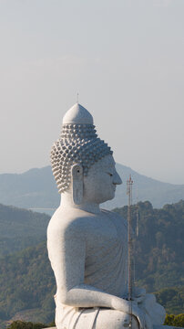 Aerial view of the Big Buddha Phuket statue in profile overlooking lush green hills and the Andaman Sea Karon, Phuket, Thailand.
