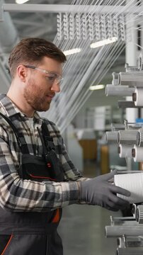 Factory worker replacing polypropylene thread spool on machine