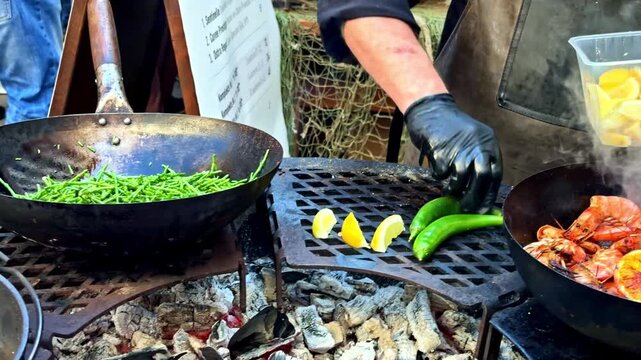 Professional cook grilling prawns, oysters, and green beans with lemon on a charcoal fire